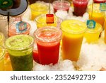 Small photo of bright fruit smoothies in cups on the market close-up. kiwi smoothie, watermelon smoothie, mango smoothie. drinks to go