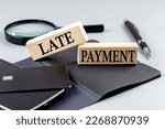 LATE PAYMENT text on a wooden block on black notebook , business concept