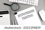 Small photo of Hypothesis testing written on paper with office tools and keyboard on grey background