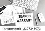 Small photo of SEARCH WARRANT text written on a notebook on grey background with chart and keyboard, business concept