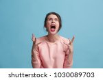 Screaming, hate, rage. Crying emotional angry woman screaming on blue studio background. Emotional, young face. Female half-length portrait. Human emotions, facial expression concept. Trendy colors