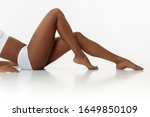 Anti-cellulite and epilation. Slim tanned woman's legs on white studio background. African-american model with well-kept shape and skin. Beauty, self-care, weight loss, fitness, slimming concept.