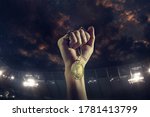 Champion. Award of victory, male hands tightening the golden medal of winners against cloudy dark sky. Sport, competition, championship, winning, achieving the goal. Prize for success and honor.