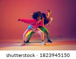 Small photo of Stylish man and woman dancing hip-hop in bright clothes on green background at dance hall in neon light. Youth culture, hip-hop, movement, style and fashion, action. Fashionable portrait.