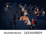 Cinema in quarantine. Coronavirus pandemic safety rules, social distance during movie watching. Men, women in protective face mask sitting in a rows of auditorium. Leisure time, youth culture concept.