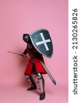 Small photo of Brave warrior. Portrait of medieval warrior or knight wearing armor clothing holding shield and sword isolated over pink background. Comparison of eras, history, renaissance style. Fashion, vintage