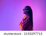 Profile view of young girl with afro hairdo in cotton shirt isolated on purple background in neon light. Concept of beauty, art, fashion, youth, sales and ads. Pretty woman laughing
