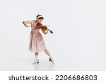 Charming beautiful young girl playing violin isolated over white studio background. Tender, lovely sound. Concept of live music, performance, retro style, creativity, artistic lifestyle