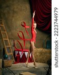 Small photo of Retro circus performance. Little flexible girl, gymnast or acrobat doing gymnastics trick over dark circus backstage background. Concept of sport, art, fashion, vintage style.