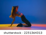 Portrait of young girl dancing high heel dance in stylish clothes over blue background in neon light. Concept of dance lifestyle, modern style, contemporary dance, youth culture, self-expression