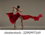 Small photo of Toreador style. Artistic ballet performance with young man dancing with red fabric over grey studio background. Concept of art, classical dance, inspiration, creativity, fashion, beauty, choreography
