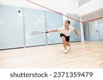 Young concentrated man in sportswear playing, training squash on squash court. Leisure healthy time. Concept of sport, hobby, healthy and active lifestyle, game, gym, ad