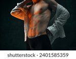 Small photo of Cropped male body, muscular torso against dark textured studio background. Young man in white shirt and boxers. Concept of men's beauty, health, body art and aesthetics, care, sportive lifestyle