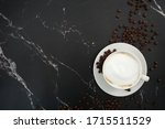 cup of coffee with beans, with black marble background
