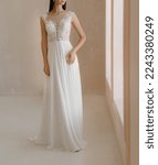 Small photo of Front view of beautiful bride in the white wedding dress with deep neckline. Gorgeous sleeveless wedding dress decorated with lace