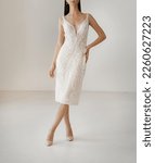 Small photo of Classic short white wedding dress with cleavage decorated with floral lace. Bride dressed in the sleeveless white wedding dress with deep neckline