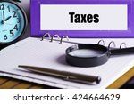 Taxes - Purple Office Folder on Background of Working Table with Magnifying glass,  a pen and clock -business and finance concept