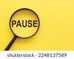 Magnifying glass with the word PAUSE on yellow background. Copy space