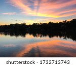 Beautiful, colourful sunset at Tuscaloosa River in Tuscaloosa, Alabama, USA. Dark woods line its lakesides and reflect in the water. A pure invitation to visit and travel the South of the U.S.