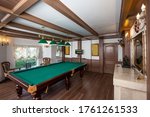 Billiard room interior. Green table for game. Old german style design. Brown wooden decor on the ceiling, walls and floor.