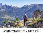 Active senior caucasian man hiking in Dolomiti mountains with backpack, enjoying his adventure. Carezza, Dolomites Alps, South Tyrol, Italy, Europe.