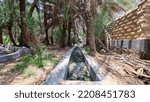 Small photo of Al Ain, United Arab Emirates â€“ July 20, 2022: Traditional Falaj, an ancient system of irrigation by water channels, at Al Ain Lush Oasis in Al Ain, Abu Dhabi.
