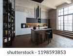 luxury studio apartment with a free layout in a loft style in dark colors. Stylish modern kitchen area with an island, cozy bedroom area with fireplace and personal gym