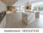 trendy modern interior design of a large studio in white and beige colors with large floor-to-ceiling windows. area of ​​white kitchen with an island and a recreation area