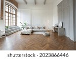 minimalistic interior of an ultra modern open plan apartment with white and gray walls with a relief. gray stylish upholstered furniture and huge windows