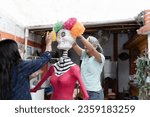 Small photo of Two Hispanic women are decorating a skeleton toff for Day of the Dead celebration. Concept of Dia de Muertos tradition in Mexico