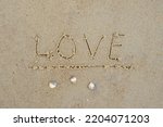 The inscription LOVE on sand, inscription LOVE and MUSZELKI, concept of holiday love or summer affair