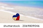 Small photo of Flag of the Philippines in the shape of a heart on a sandy beach. The concept of the best vacation in Philippine resorts