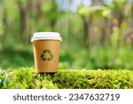 The concept of nature conservation and zero waste. Eco-friendly paper cup with a recycling sign on the background of wildlife
