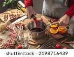 Woman is pouring wine to cook mulled wine. Process of making a warming traditional beverage, a cozy festive atmosphere.