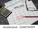 2023 US tax day calendar reminder with tax forms, calculator and glasses.