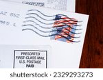 Small photo of Close up of a cancelled US postage stamp in pile of mail. Concept of pending postage rate increase on July 9, 2023.
