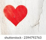 Red love heart spray painted on wall background. One red heart painted on concrete fence backdrop. Happy Valentines day. 14th february.