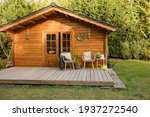 Nice wooden hut in a green garden. Garden shed with chairs and flowers. Spring mood. Drinking tea outside in spring. 