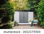 Small photo of Gray garden shed in summer. Lots of pots of flowers next to a plastic garden shed. Relax in the garden. Big garden in Germany