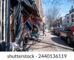 Small photo of Philadelphia, PA, USA 03-14-2024 A person walks into an antique shop with flags that read 'Antiques,' and 'Open' in front of Anastacia's Antiques on Bainbridge Street in center city. Antiques