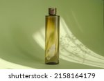 cosmetic bottle on green background with sunlight and floral shadow