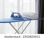 Small photo of Iron on ironing board with clothes - household concept, domestic life