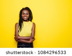 Beauty portrait of young african american girl posing on yellow background, looking at camera.