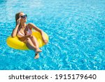 Happy young woman in bikini with rubber inflatable float, playing and having a good time at water fun park pool, on a summer hot day