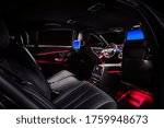 Car interior with comfortable black leather seats, displays and red ambient light.