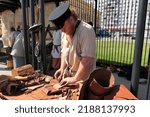 Small photo of Nizhny Novgorod, Russia, st. Sovnarkomovskaya 13, Nizhny Novgorod Fair, 07.24.2020. Professional tanner or furrier. Man makes leather products.Leatherworker, saddler profession. High quality photo
