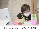 A child in quarantine in a medical mask receives an online education for a tablet at home