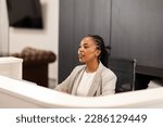 Small photo of The young African-American female receptionist sits behind the reception desk and waits for the guests.