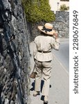 Small photo of Woman with Strawhat and Handbag Walking on the Street with Stone Wall in Ascona, Ticino in Switzerland.