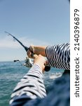 Small photo of A fisherman with a fishing rod in a cap and sailor suit on a summer day. Fishing rod in hand. A fisherman against the sky. Sea fishing.